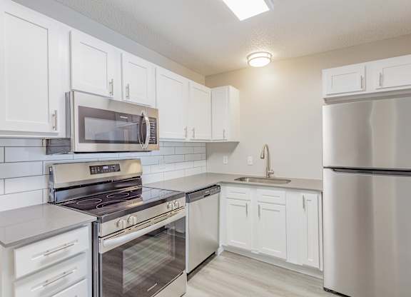A modern kitchen with white cabinets and stainless steel appliances.