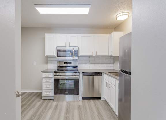 A kitchen with white cabinets and stainless steel appliances.