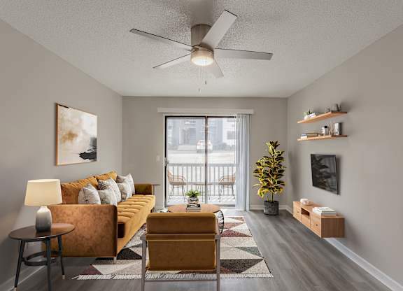 A living room with a yellow couch and a ceiling fan.