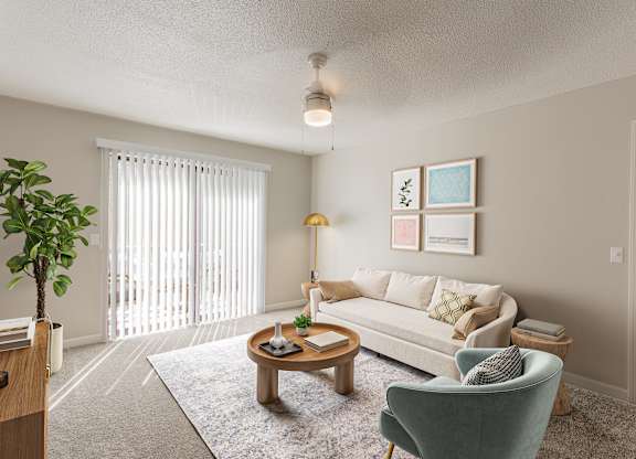 A living room with a white couch, a green armchair, a wooden coffee table, and a potted plant.