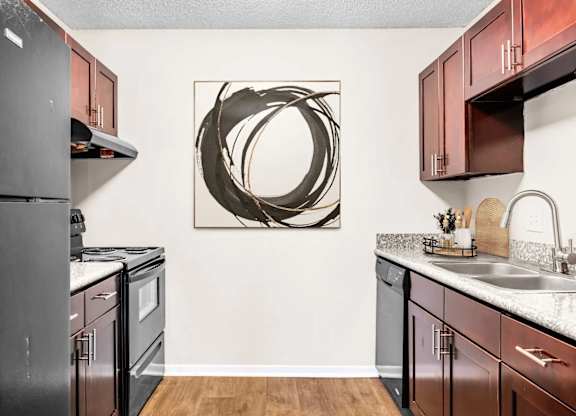 A modern kitchen with dark wood cabinets and a large abstract metal artwork on the wall.