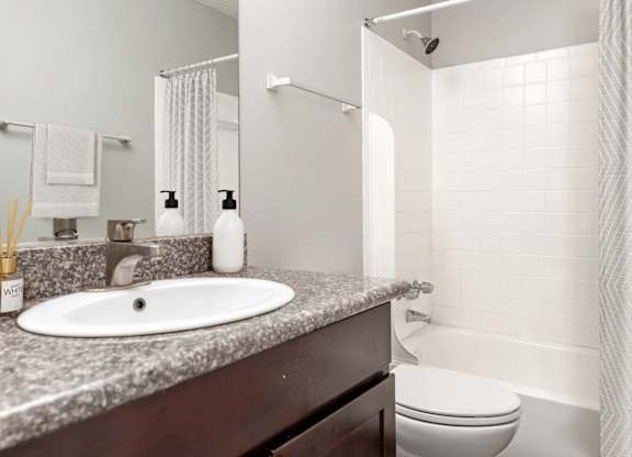 A white bathroom with a sink, toilet, and shower.
