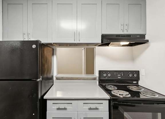 A black refrigerator is in a kitchen with a stove and oven.