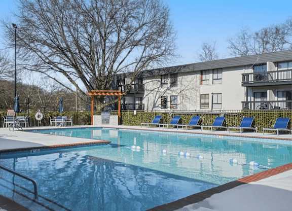 A swimming pool in front of a building with a tree in the background.