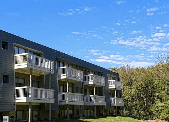A multi-story apartment building with balconies and a clear blue sky above.