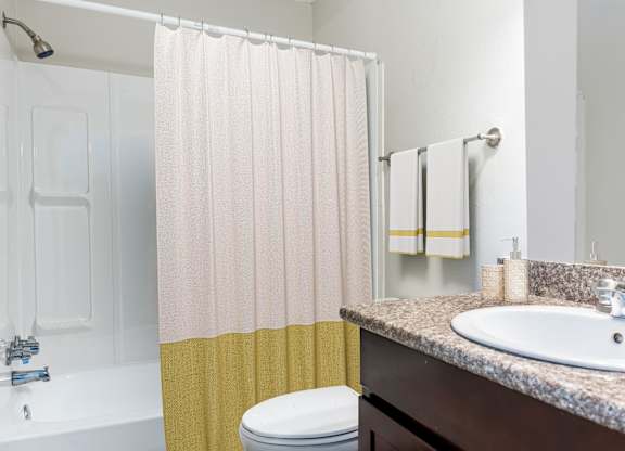 A bathroom with a toilet, sink, and shower curtain.