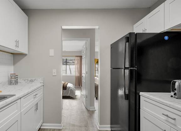 A black refrigerator is in a white kitchen.