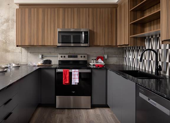 A modern kitchen with a black countertop and stainless steel appliances.at Damask, Windsor, ON