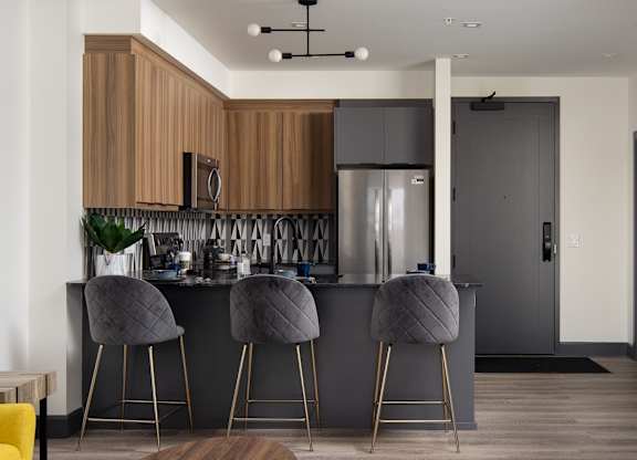 A modern kitchen featuring wood grain upper cabinets, dark stone countertops and stainless steel appliances at Damask, Windsor