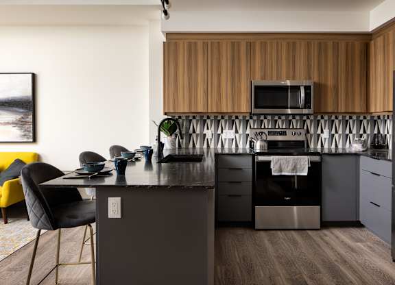 A modern kitchen with a wooden backsplash and stainless steel appliances.at Damask, Windsor, ON N8S 0B7