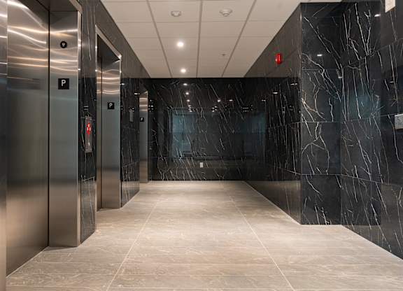A long hallway with marble floors and walls and elevators on the side at Damask, Windsor, N8S 0B7
