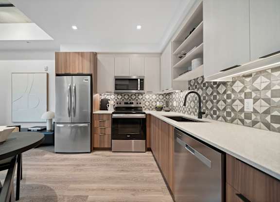 A modern kitchen with a stainless steel refrigerator and a black and white tiled backsplash