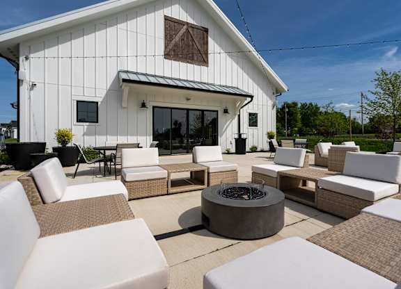 A white patio with a fire pit and chairs.