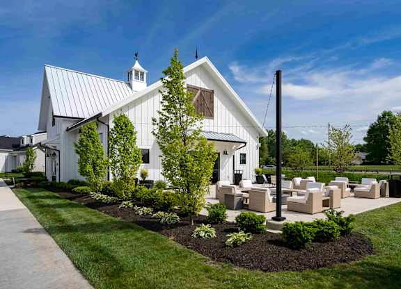 A white building with a black roof and a tree in front.