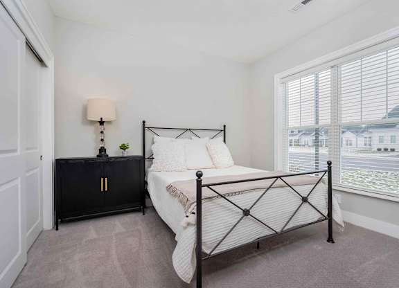 A bedroom with a black metal bed frame and a white bedspread.