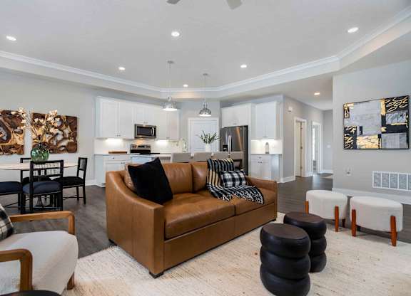 A modern living room with a brown leather couch and a dining table with chairs.