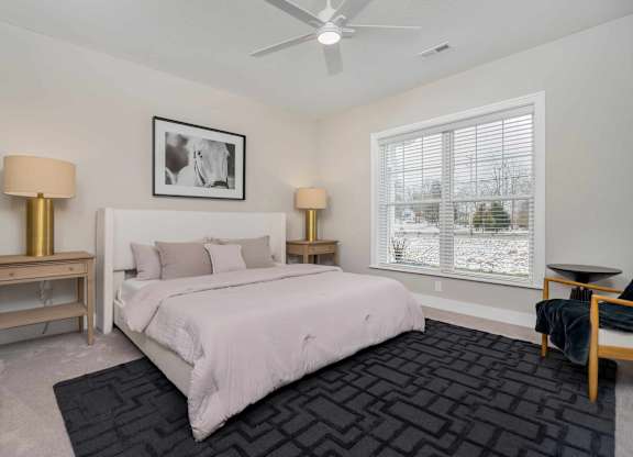A bedroom with a large bed, two lamps, and a picture on the wall.