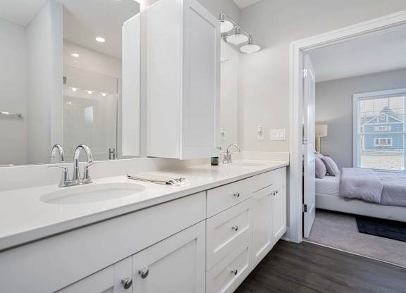 A white bathroom with a double sink and a mirror above it.