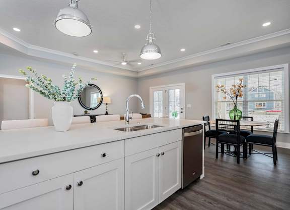 A modern kitchen with white cabinets and a wooden floor.