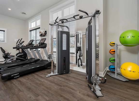 A home gym with a treadmill, a weight machine, and a yellow exercise ball.