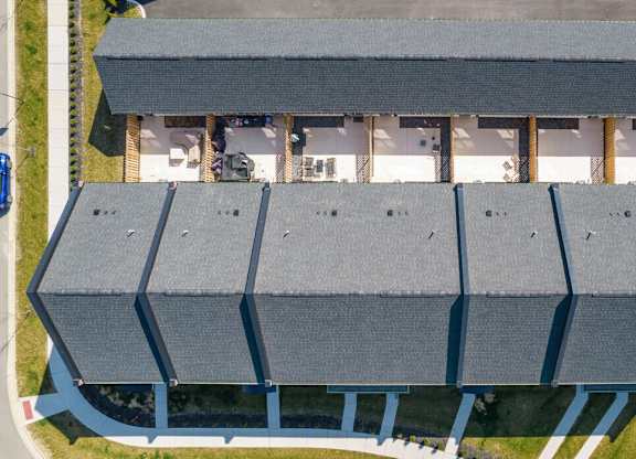 A large building with a grey roof and a parking lot in front.