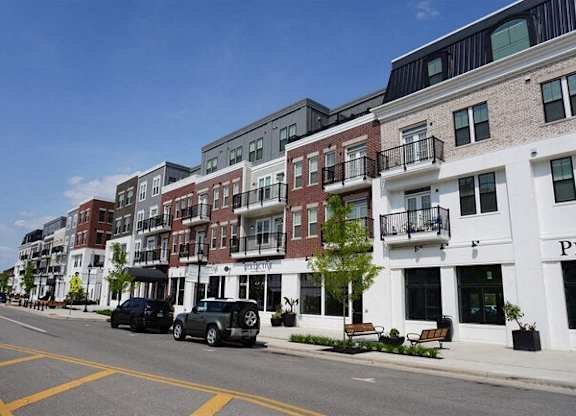 A street view of a row of buildings with cars parked on the side.