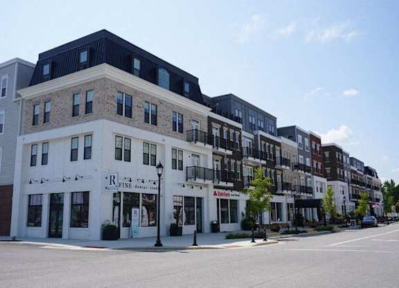 A street view of a row of buildings with the frontmost one having a sign that says "R Fine Dry Goods".