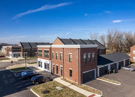 A parking lot in front of a brick building with a clear blue sky.