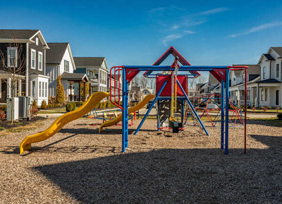 A playground with a yellow slide and a red and blue structure.