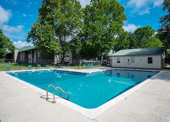 A large swimming pool surrounded by trees and buildings at Sawbranch Apartments, Summerville, SC