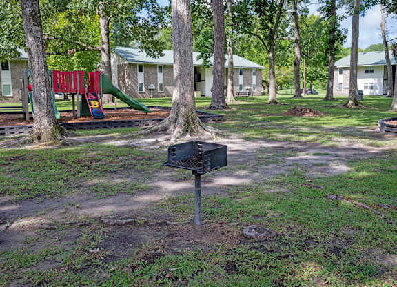 A black mailbox sits on a grassy area in front of a playground and houses at Sawbranch Apartments, South Carolina