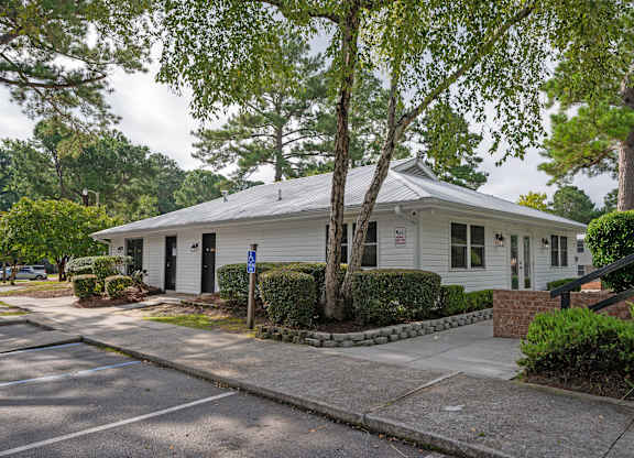 A white house with a blue sign in front of it at Woodlocke Apartments, South Carolina