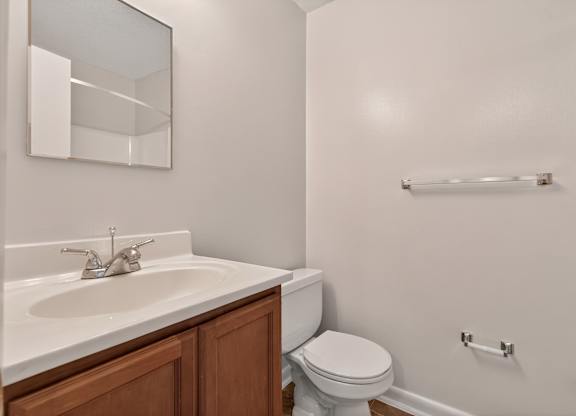 A white toilet sits next to a sink in a small bathroom at Woodlocke Apartments, South Carolina, 27461