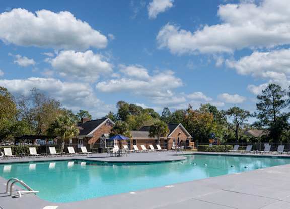 A large swimming pool surrounded by lounge chairs and trees at The Preserve at Pine Valley Apartments, Wilmington, 28412
