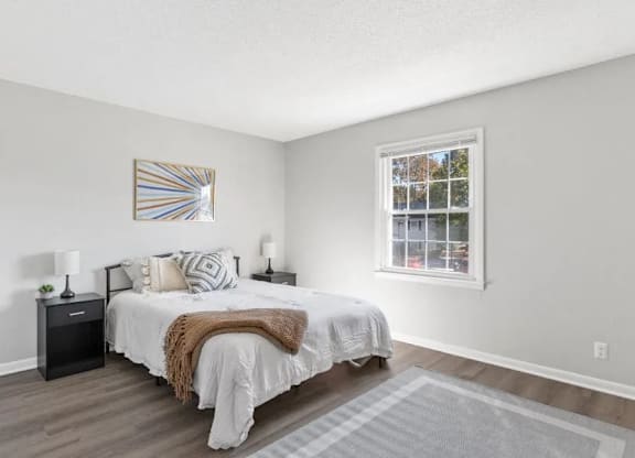 A bedroom with a bed, nightstands, and a window at The Preserve at Pine Valley Apartments, Wilmington, NC