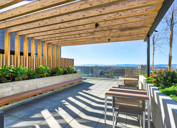 A wooden patio with chairs and a table with a view of the city.at Eleven Fifty Clay Street, Oakland  