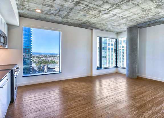 A spacious room with wooden floors and a large window overlooking a cityscape.at Eleven Fifty Clay Street, Oakland, 94607  