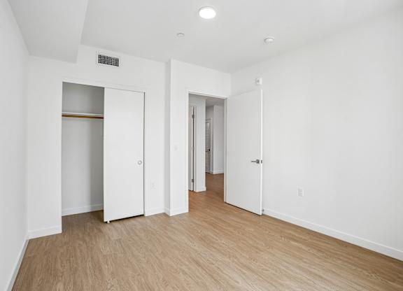 A white room with wood flooring and a few doors.