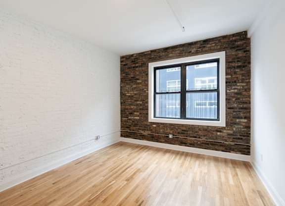 A room with a brick wall and a window.