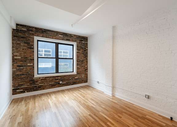 A room with a brick wall and wooden flooring.