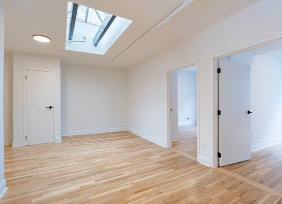 A room with wooden floors and white walls with a skylight.