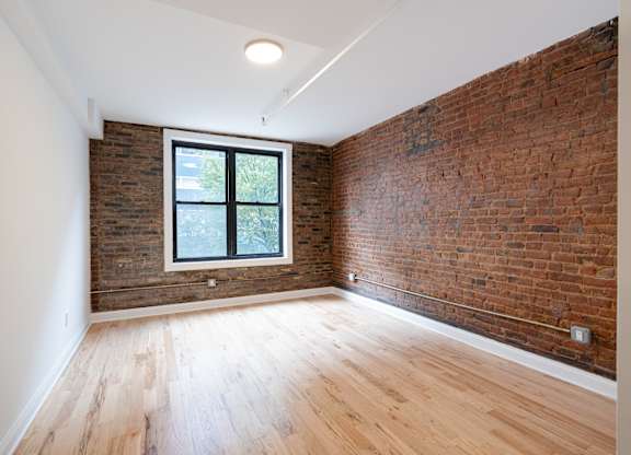 A room with a window and a brick wall.