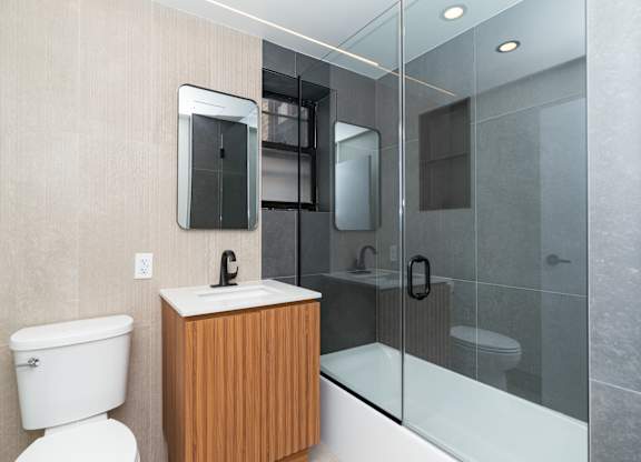 A modern bathroom with a toilet, sink, and shower.