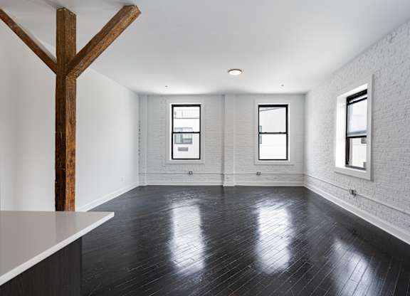 A large empty room with wooden floors and white walls.