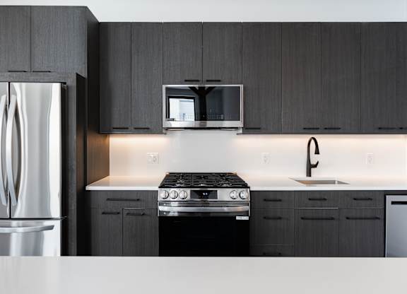 A modern kitchen with a stainless steel refrigerator and a black stove top oven.