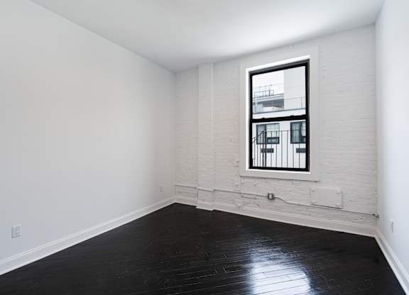 A room with a window and a wooden floor.