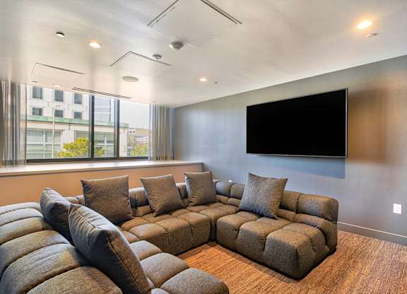 A living room with a large sectional sofa and a flat screen TV mounted on the wall.at Eleven Fifty Clay Street, Oakland, CA 94607  