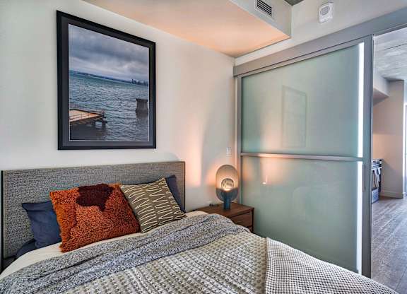 A bedroom with a bed, nightstand, and a picture on the wall.at Eleven Fifty Clay Street, Oakland, CA  