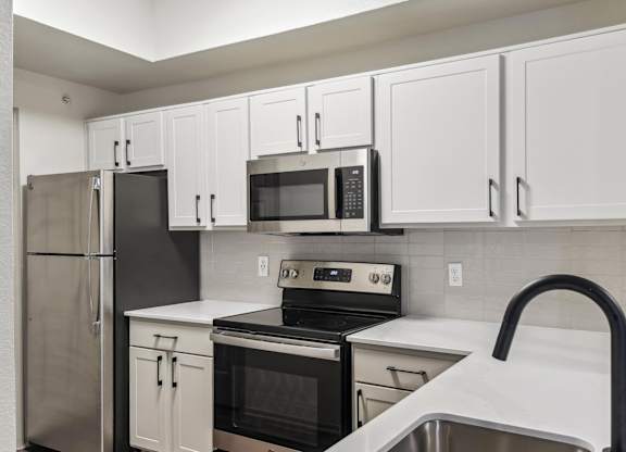 A kitchen with white cabinets and black appliances.at Onyx183, Austin, TX  