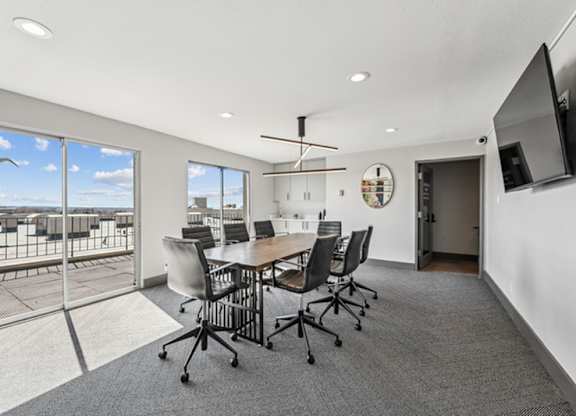 A conference room with a table, chairs, and a television. at The Lex At Lowry, Denver, CO
